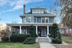 a large house with many windows and bushes on the front lawn in front of it