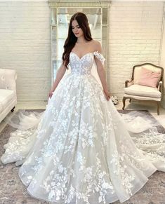 a woman in a white wedding dress standing on a carpeted floor with her hands behind her back