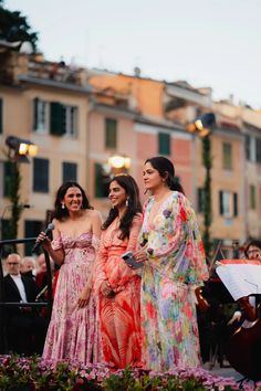 three women standing next to each other in dresses