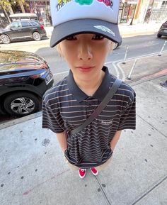 a young boy wearing a hat on the sidewalk