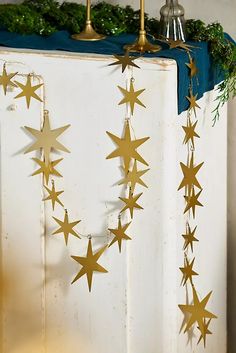 some gold stars hanging from the side of a white cabinet next to a candle holder