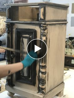 a woman is painting an old wooden cabinet