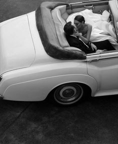 a man and woman sitting in the back of a white car with their arms around each other