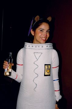 a woman in a white costume holding a bottle and wearing a cat costume on her head