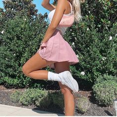 a woman in a pink skirt and white top posing for the camera with her hand on her head