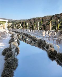 an outdoor wedding venue set up with white chairs and greenery around the pool area