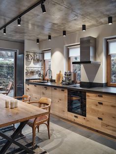 a kitchen with wooden cabinets and black counter tops next to a dining room table that has chairs around it