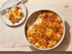 a casserole dish on a wooden table next to a plate with a fork