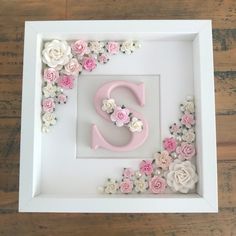 a white frame with pink and white flowers surrounding the letter s