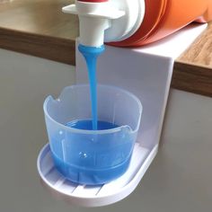 an orange cup with blue liquid being poured into it