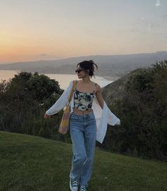 a woman walking in the grass with her shirt open