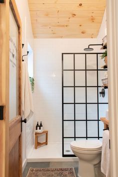 a white toilet sitting next to a bath tub in a bathroom under a wooden ceiling