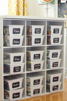 an organized storage unit with chalkboard labels and bins