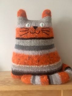 a knitted cat sitting on top of a wooden table