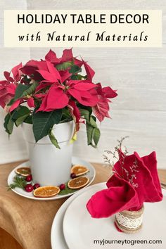 holiday table decor with natural materials including poinsettis, orange slices and cranberries