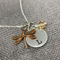 "The dragonfly symbolizes change, transformation, adaptability, and self-realization. Wear it as a reminder for positive change. 5/8\" silver alkeme' disc is hand stamped with initial and has beveled edge. Copper dragonfly charm has intricate filagree design and measures 5/8\". Includes handmade iridescent crystal bead charm. Hangs from a .925 sterling silver chain. Hypo-allergenic and nickel free. You choose the length. Fast shipping! Most orders ship in 1 business day from our studio in Ohio." Adjustable Silver Inspirational Charm Necklace, Inspirational Adjustable Silver Charm Necklace, Adjustable Silver Necklace, Filagree Design, Bronze Wedding Anniversary, Silver Dragonfly Necklace, Bronze Wedding, Gifts For Best Friend, Dragonfly Charm