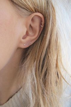 a close up of a person's ear with two small piercings on it