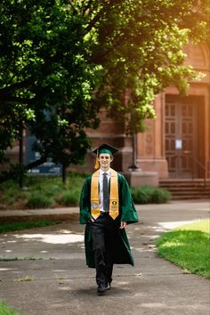 a man in a graduation gown walking down a path with his cap and gown on