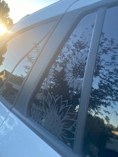 the sun shines brightly through the window of a white car that is parked in front of some trees