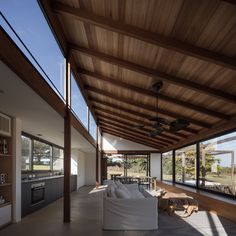 a living room filled with furniture and lots of windows next to a wall covered in wood