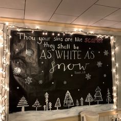 a chalkboard with words written on it in front of a christmas scene and lights