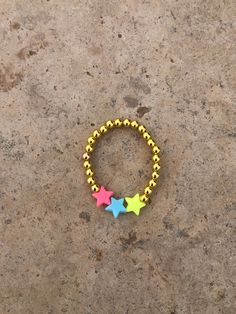 This bracelet is a gold beaded bracelet with plastic colorful stars Adjustable Star-shaped Bracelets With Colorful Beads, Adjustable Star Shaped Bracelet With Colorful Beads, Adjustable Star-shaped Jewelry With Spacer Beads, Adjustable Star Shaped Jewelry With Spacer Beads, Multicolor Star-shaped Bracelet With Colorful Beads, Trendy Star-shaped Beaded Jewelry, Trendy Star Shaped Beaded Jewelry, Star-shaped Beaded Party Bracelets, Handmade Star-shaped Gold Bracelets