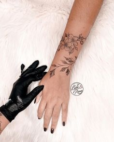 a woman's hand with black gloves and tattoos on it, next to a white fur rug