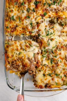 a casserole dish with meat and cheese being lifted from the casserole