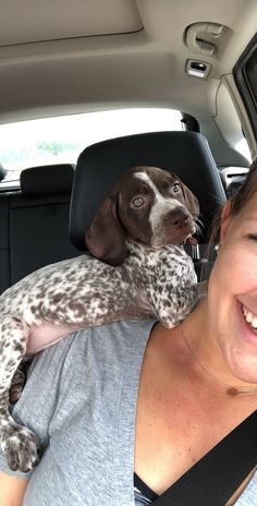 a woman holding a dog in the back seat of a car