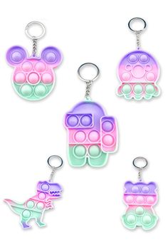 four key chains with different colors and shapes on them, one is pink, the other is blue