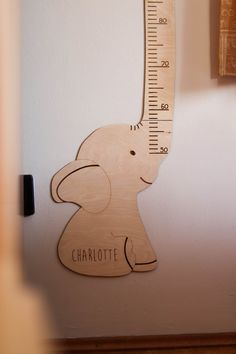 a wooden growth chart with an elephant on it's back and the word charlotte written in white