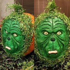 two pumpkins with green faces and grass on them