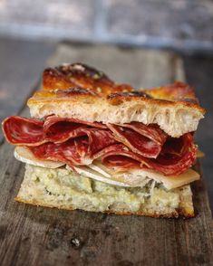 a sandwich with meat and cheese on a cutting board