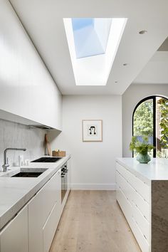 a kitchen with white cabinets and an open skylight