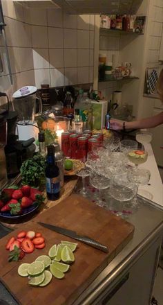 a woman standing in a kitchen next to a cutting board filled with fruit and vegetables