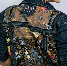 the back of a woman's jean jacket with patches and stars on it,