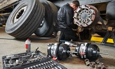 a man working on an engine in a garage next to some tires and wrenches