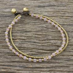 Thai artisan Tiraphan Hasub carefully chooses stones of natural rose quartz, beading the length of this anklet. The beads are alternated with petite brass beads, accompanied by a beaded strand of brass. The fashionable anklet is completed with two ringing brass bell buttons, giving it an adjustable length. materials: Rose quartz, brass, polyester cord Button clasp Adjustable Natural stone - some variations in color and/or pattern are to be expected 9.25 in. min L - x 9.75 in. max L x 0.3 in. W Diy Anklets, Bling Makeup, Christmas Beading, Rose Quartz Bracelet Beads, Diy Bling, Jewlery Necklace, Diy Beading, Beaded Jewelry Necklaces, Beaded Anklet