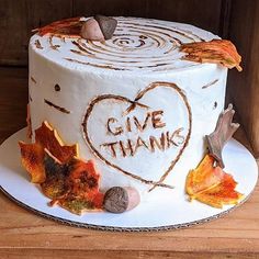 a white cake decorated with leaves and the words give thanks