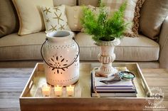 a living room with a couch, coffee table and vase on it's tray