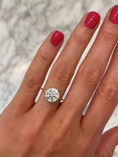 a woman's hand with a red manicured nail polish holding a diamond ring