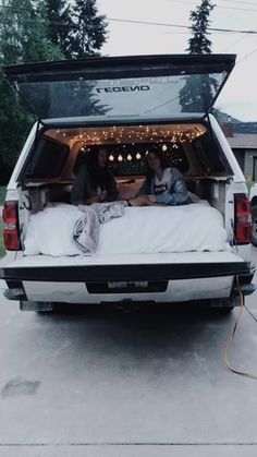 two people are sitting in the back of a truck with their dog on it's bed