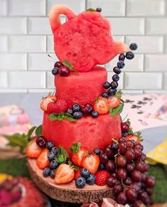 a watermelon cake with berries and strawberries on the top is surrounded by other fruit