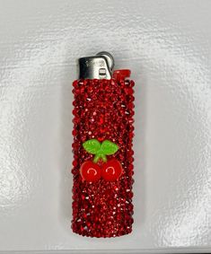 a red lighter with a green leaf on it's side and two tomatoes in the middle