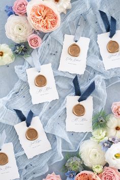 wedding favors and flowers on a blue cloth with white paper tags that say i do