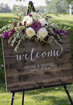 a welcome sign with flowers and greenery on it