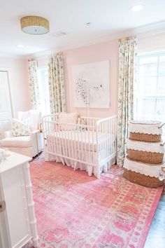 a baby's room with pink walls and floral curtains