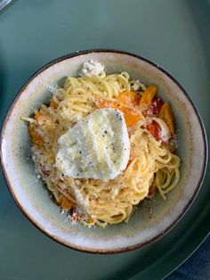 a bowl filled with pasta and cheese on top of a blue tablecloth next to a fork