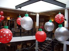 red and silver christmas ornaments hanging from the ceiling in a shopping mall with balconies