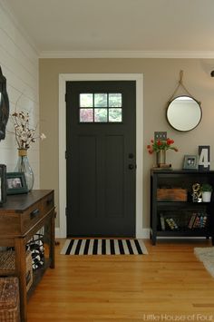 a living room with a black door and white walls, wood floors and rugs on the floor